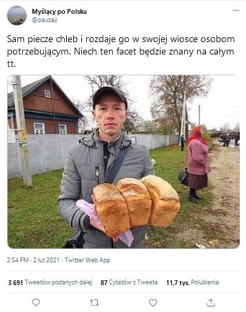 Zdjęcie z TT przedstawiające w centralnym miejscu mężczyznę trzymającego bochenki chleba w rękach. Za nim widać drewniany dom, mur, starszą kobietę a w oddali kilka osób.