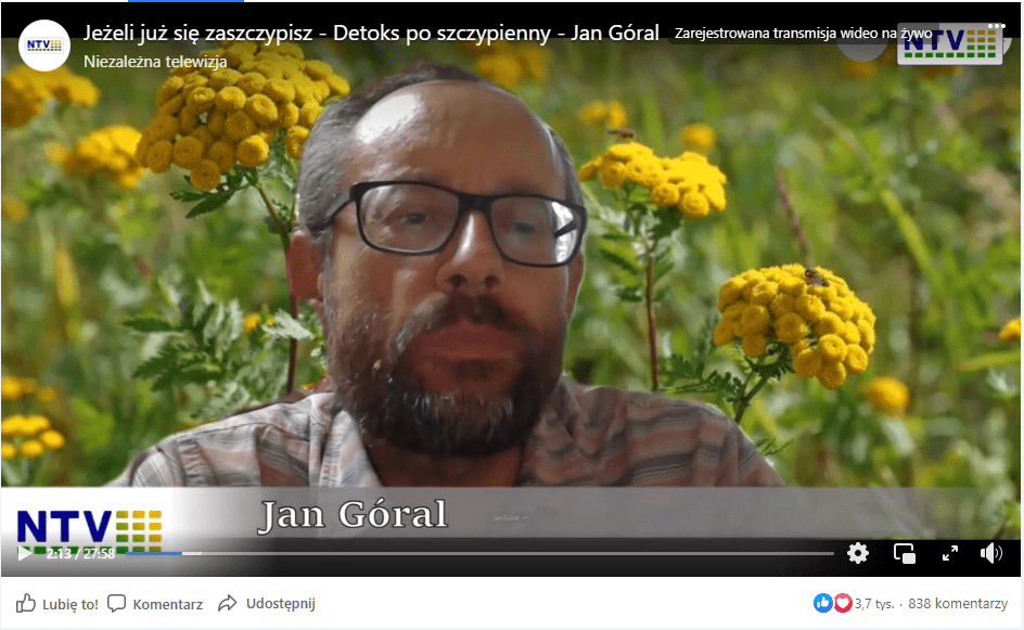 Zrzut ekranu posta na Facebooku, w którym udostępniono rozmowę z Janem Góralem. W prawym górnym rogu znajduje się logo Niezależnej Telewizji. W kadrze znajduje się twarz Jana Górala: dojrzałego mężczyzny w okularach z brodą. W tle ustawiono tło, na którym jest łąka z żółtymi kwiatami.