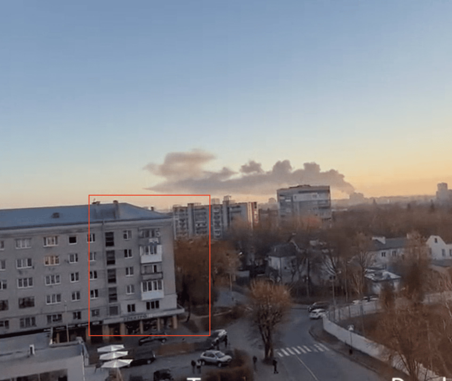 Zrzut ekranu z widocznym w ostatnich sekundach nagrania budynkiem i kłębami dymu w oddali.