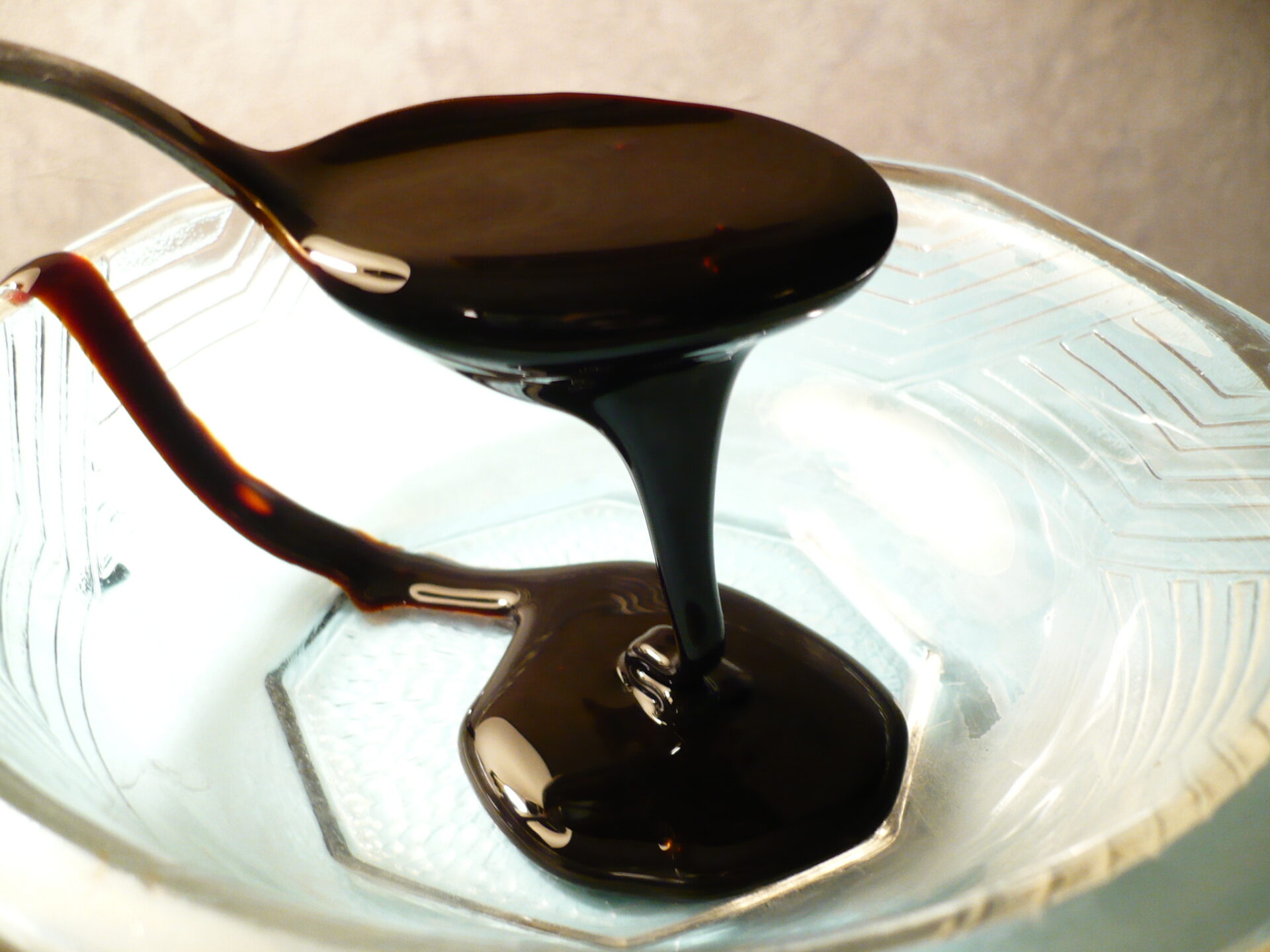 Melasa w postaci gęstego, brązowego syropu spływającego z łyżki stołowej; Źródło: https://upload.wikimedia.org/wikipedia/commons/8/8f/Blackstrapmolasses.JPG, autor: Badagnani, licencja: CC 3.0 Uznanie autorstwa