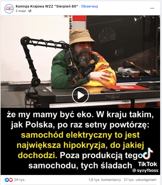 Nagranie z TikToka opublikowane na Facebooku. Brodaty mężczyzna w okularach przeciwsłonecznych czapce ubrany w kolorową bluzę siedzi za biurkiem przed mikrofonem ustawionym na wysięgniku po prawej stronie