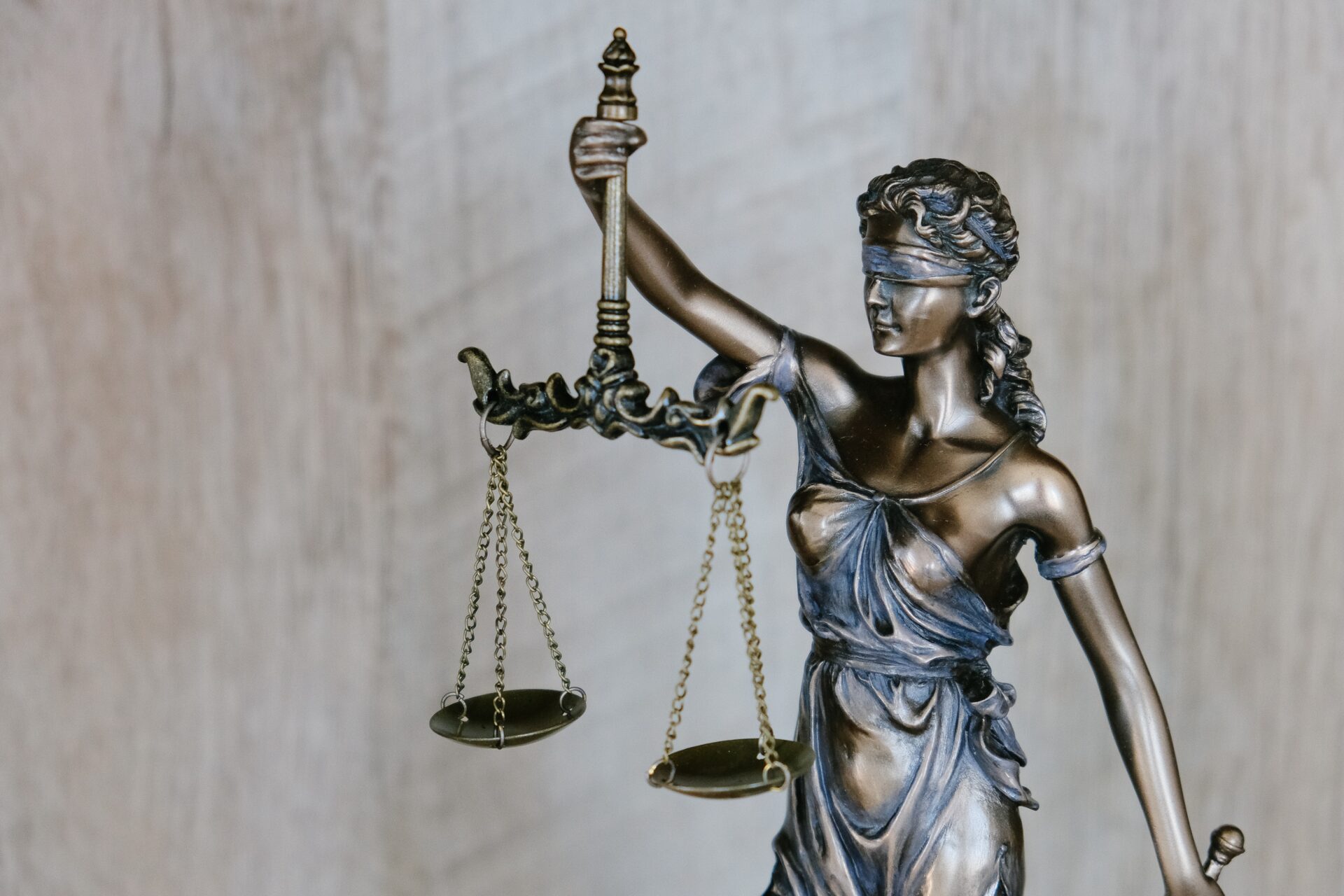 Brązowa figurka bogini sprawiedliwości — kobiety z zawiązanymi oczami trzymającej szalę.