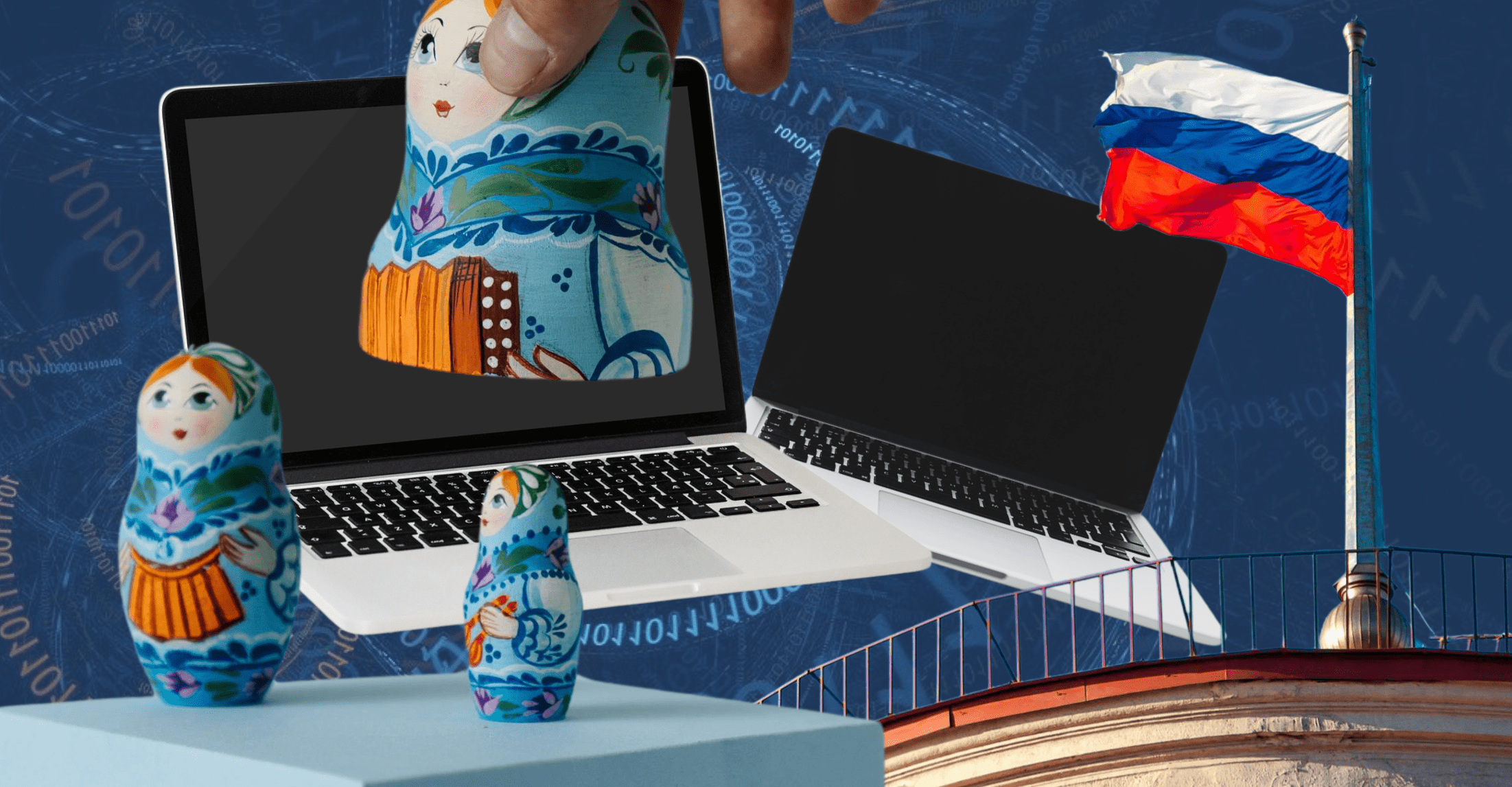 Trzy kolorowe matrioszki różnych rozmiarów, za nimi dwa laptopy, a obok budynek z rosyjską flagą.