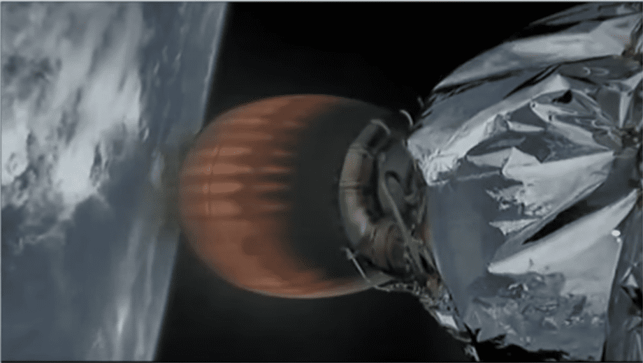 Na grafice widoczna jest część rakiety Falcon 9 w trakcie lotu w kosmos. Po lewej stronie znajduje się planeta Ziemia, od której rakieta się oddala. Silnik rakiety jest rozgrzany do czerwoności. Na jego powierzchni widzimy dokładnie elementy i komponenty, takie jak przewody. Na silniku znajduje się mały niezidentyfikowany obiekt o owalnym kształcie.