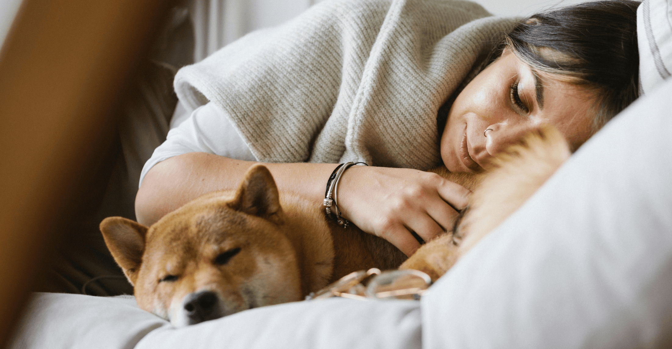 Kobieta leżąca na lewym boku, a przy niej rusy mały pies rasy akita
