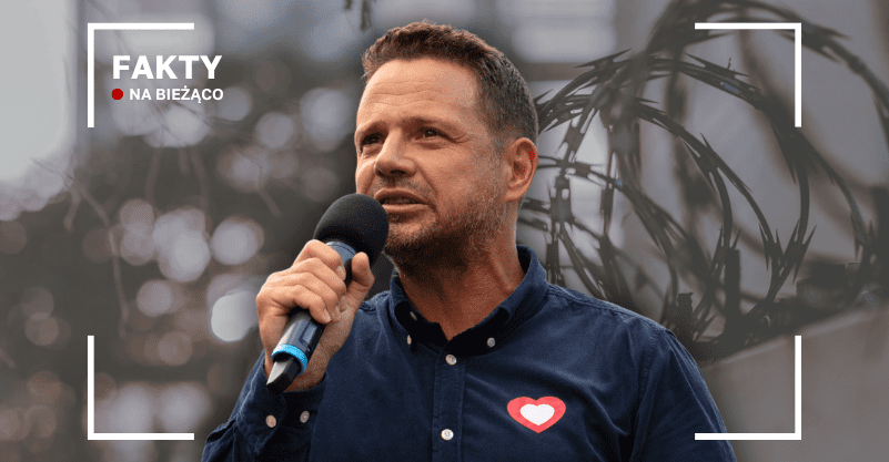 Rafał Trzaskowski z mikrofonem na tle drutu kolczastego
