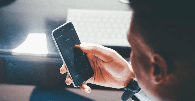 w tle mężczyzna wpisujący hasło w telefonie