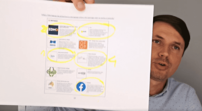 Grzegorz Płaczek trzyma wydrukowaną kartkę ze strony Demagoga z listą grantów, które organizacja otrzymała na swoją działalność. Zaznaczył żółtym zakreślaczem wybrane organizacje.